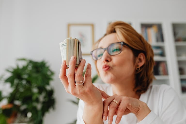 A woman happily kisses a wad of cash in a bright, indoor setting.