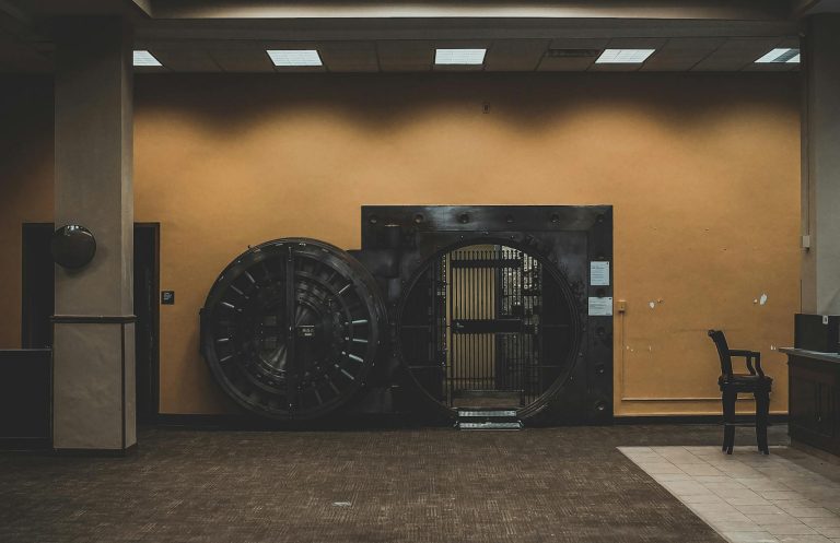 A spacious bank interior showcasing a large, open vault door under a modern ceiling.